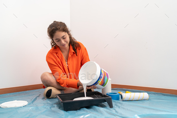 Woman pouring white paint to a plate to paint the house