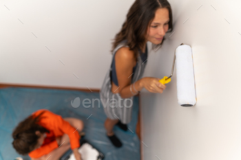 Women using paint roller to paint the wall