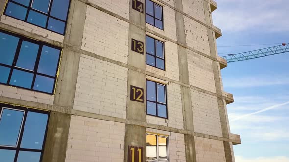 Aerial view of high residential apartment building with storey numbers on wall under construction