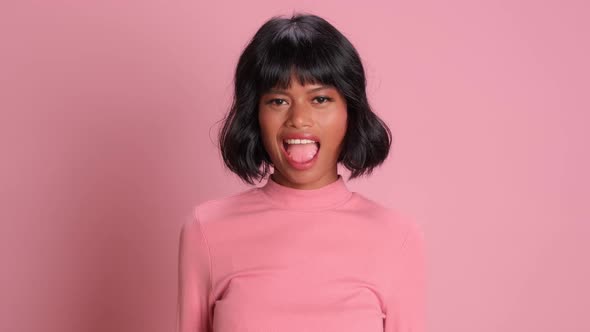 Close Up of Playful Dark Skinned Woman Flirting and Winking on Pink Background