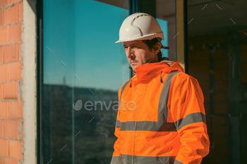 Construction engineer with protective white helmet and high visibility orange jacket on site