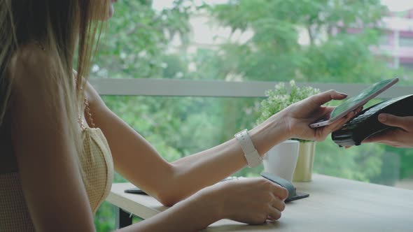 Young Asian Woman using a Mobile Phone Smart payment in the Coffeeshop 01