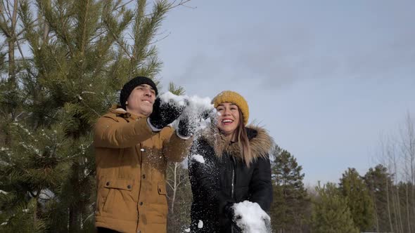 Couple Girl and Guy are Throwing a Snow Each Other in Winter Forest in Slow Motion
