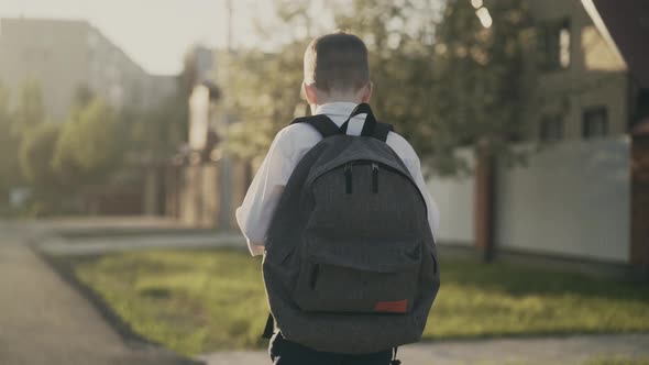 CU Tracking Back View Portrait of Schoolboy with Knapsack Behind His Back in School Uniform