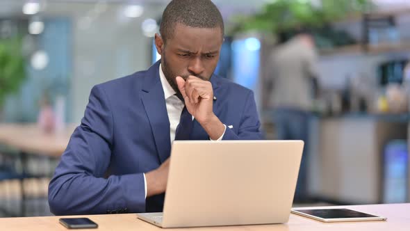 Sick African Businessman with Laptop Coughing in Office 