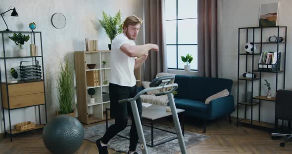 Guy in Sportswear Practicing Boxing Kicks while Doing Walking Exercises on Run Machine