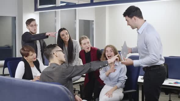 Group of Positive Colleagues Supporting Young Caucasian Man Presenting Business Idea on Tablet