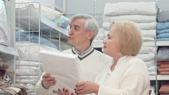 Happy Elderly Couple Laughing, Talking While Shopping for Home Goods