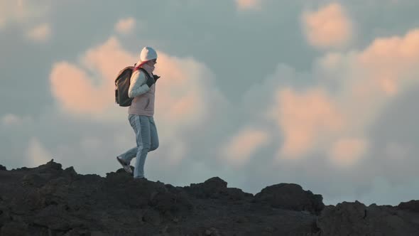 Woman in Winter Hat Jacket with Backpack Hiking on Top of Volcano Mountain Peak