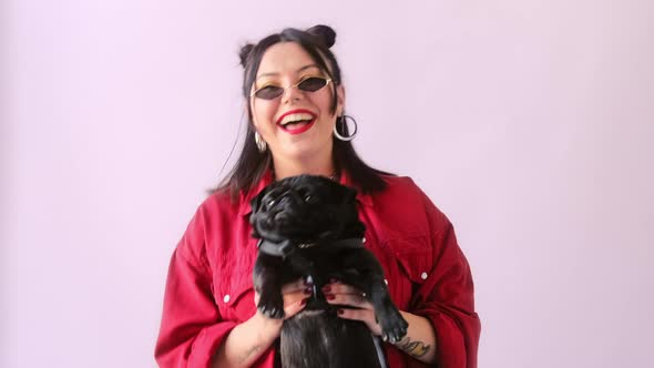 Stylish hipster woman in fashionable glasses dancing and shakes with funny pet pug