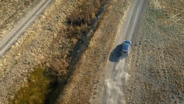 SUV Car on Countyside Dusy Road. Flying Over Grey Car Driving Through Country Dirt Road. Aerial View