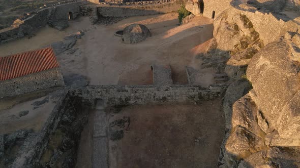 Drone flying over megalithic fortification of Monsanto Castle, Portugal. Aerial forward tilt up reve