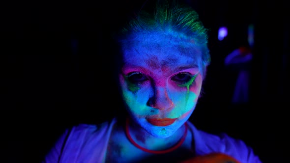 Gloomy Young Woman with Fluorescent Makeup Portrait in UV Lights in Darkness