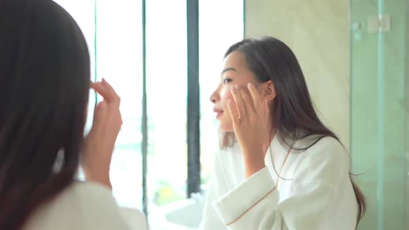 Young asian woman check her face on mirror