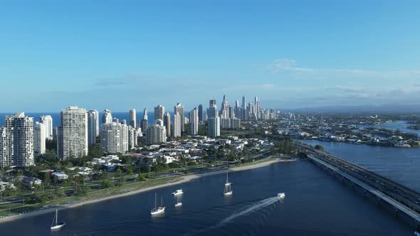 Unique high drone view of a Gold Coast skyline surrounded by water with a tram and motor vehicle bri