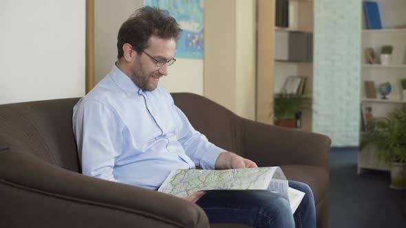 Happy Male Looking at the Map and Planning His Summer Trip, Traveling and Joy