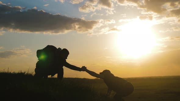 Silhouette of Helping Hand Between Two Climber. Two Hikers on Top of the Mountain, a Man Helps a Man