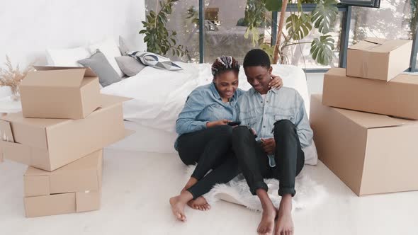 Young African-American Couple Sitting in the Modern Apartment with Boxes