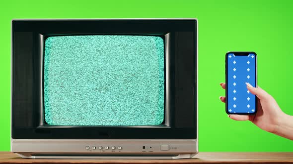 Old Television with Grey Interference Screen on Green Background and Smartphone with Blue Chroma Key