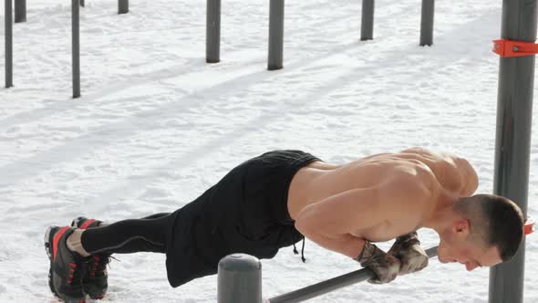 Muscular man training topless on sports field in winter