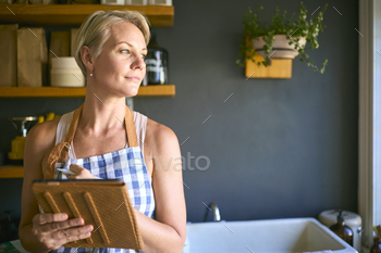 Mature Woman Working In Sustainable Plastic Free Store Checks Stock With Digital Tablet