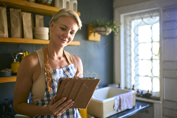 Mature Woman Working In Sustainable Plastic Free Store Checks Stock With Digital Tablet