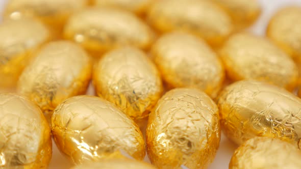 Easter chocolate golden eggs on white surface 4K 2160p UltraHD footage - Slow tilting  over golden E