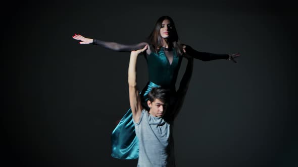 A Couple of Young Dancers Dancing Modern Choreography in the Studio on a Dark Gray Background
