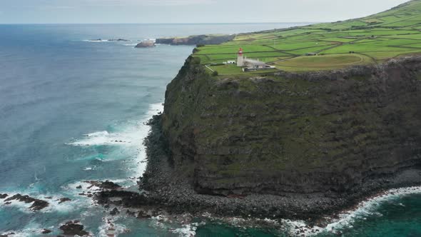 A Circular Tower on a Rocky Cliff with Green Landscape Behind