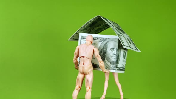 Two wooden people figures rotating and holding house build of usd dollar notes