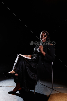 Smiling Woman Speaking to Microphone on Stage