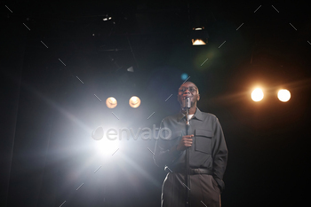 Man Speaking to Microphone Standing on Stage