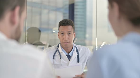 Rear Back View of Upset Couple Getting Report From Young Doctor 