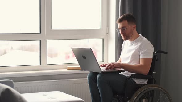 Young Man in Wheelchair Using Laptop Working at Home