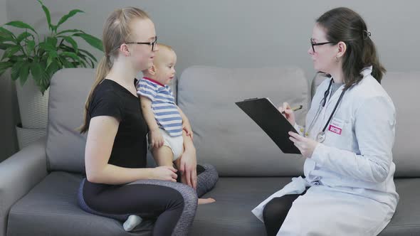 Doctor Pediatrician Woman Doing Check Up Sick Baby with Mother Living Room Exam