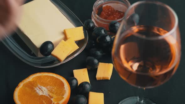 Girl Takes a Glass of Rose Wine on the Background of Snacks