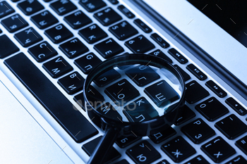 Magnifying glass on laptop computer.