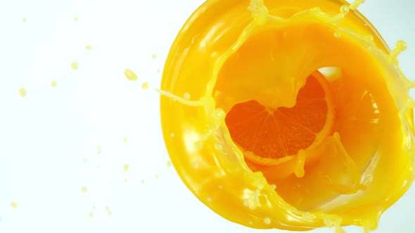 Super Slow Motion Shot of Orange Slice Splashing Into Orange Juice Isolated on White at 1000Fps