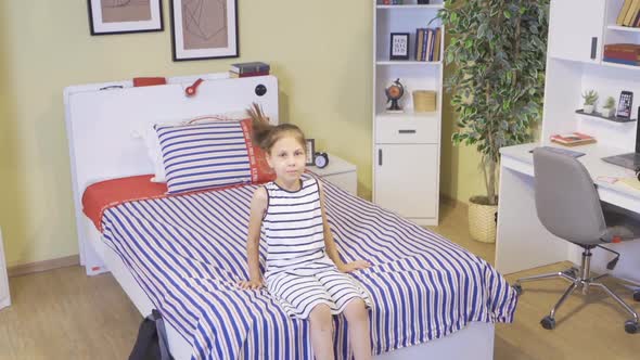Laughing at the camera, the girl jumps on her bed. alt
