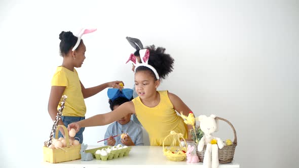 African American Kids in Funny Bunny Ears Colouring Eggs on Easter