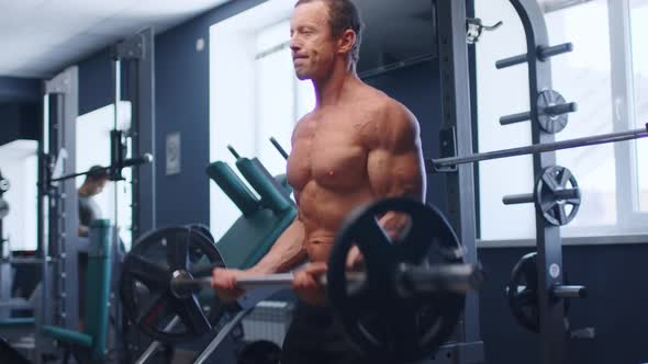 Senior Male Athlete Doing Barbell Curl Exercise in a Gym