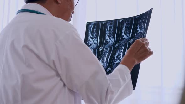 Specialist doctor examining x-ray film of patient in examination room at hospital