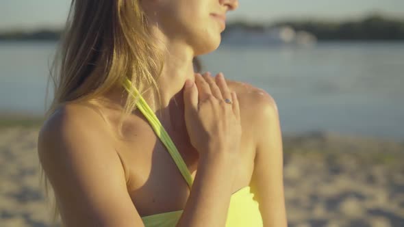 Close-up of Gorgeous Tanned Woman Applying Sunscreen on Shoulder and Smiling. Portrait of Slim