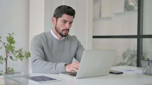 Young Man Coughing While Using Laptop in Office