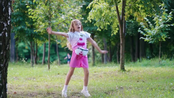 Little kid dancing in green park. Outdoor portrait of happy girl in park
