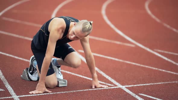 Young Muscular Concentrated Athlete at the Start of the Treadmill at the Stadium