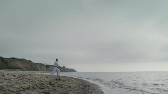 Karate Sportsman Practicing Attacks on Sandy Beach