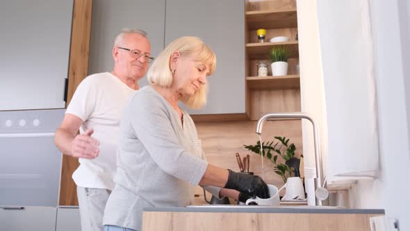 Senior Man and Woman Smiling and Washing Dishes in the Kitchen