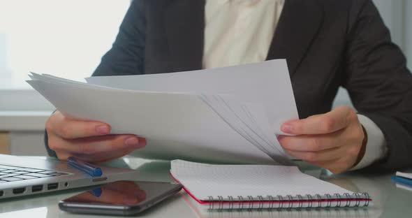 Closeup of a Business Woman's Hands Checking Reports Tax Forms and Putting Them Aside