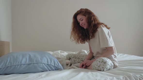 Young Redhead Girl Playing with a Kitten in Bed